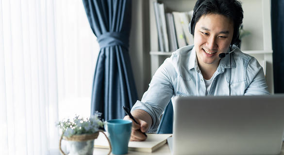 Asian guy with headset working remotely