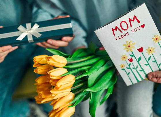 Closeup of Mother's Day celebration with yellow tulips, gift, and greeting card