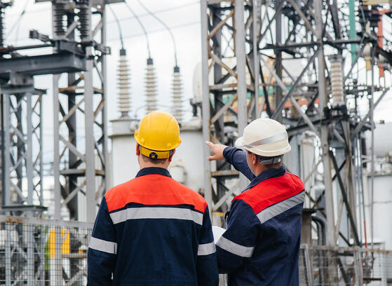 Two utility engineers inspecting modern high-voltage equipment at an electrical station.