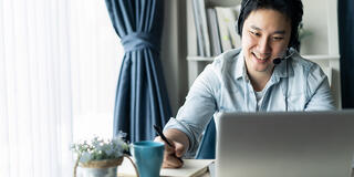 Asian guy with headset working remotely