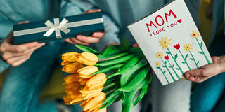 Closeup of Mother's Day celebration with yellow tulips, gift, and greeting card