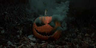 A spooky Halloween pumpkin with a menacing carved face, emitting thick smoke from its eyes and mouth