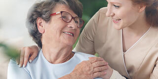 Smiling caregiver chatting with a senior woman in a joyful healthcare setting.