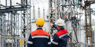 Two utility engineers inspecting modern high-voltage equipment at an electrical station.