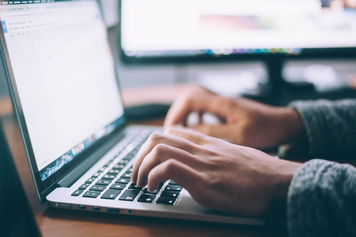 Close-up image of person typing on a laptop