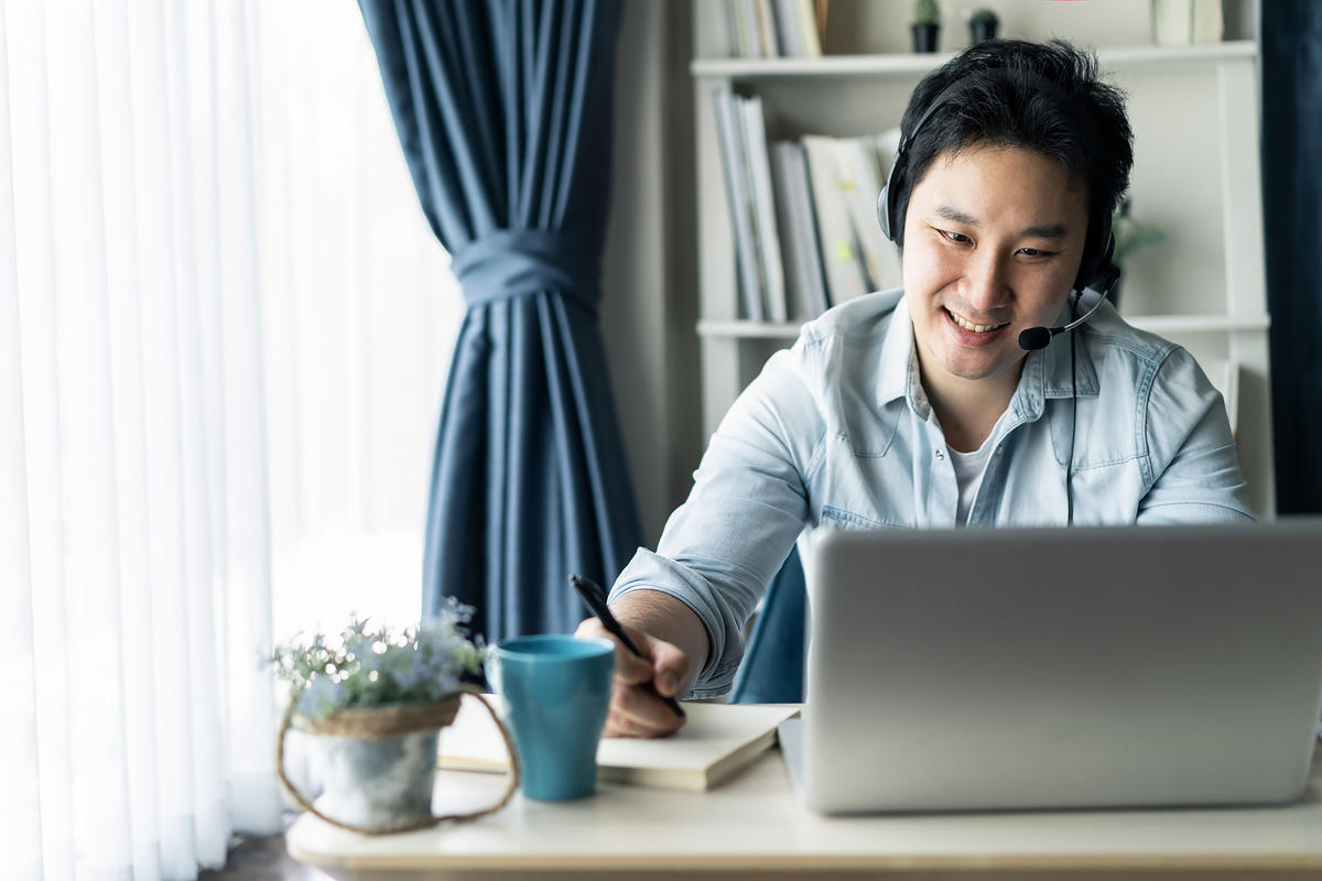 Asian guy with headset working remotely