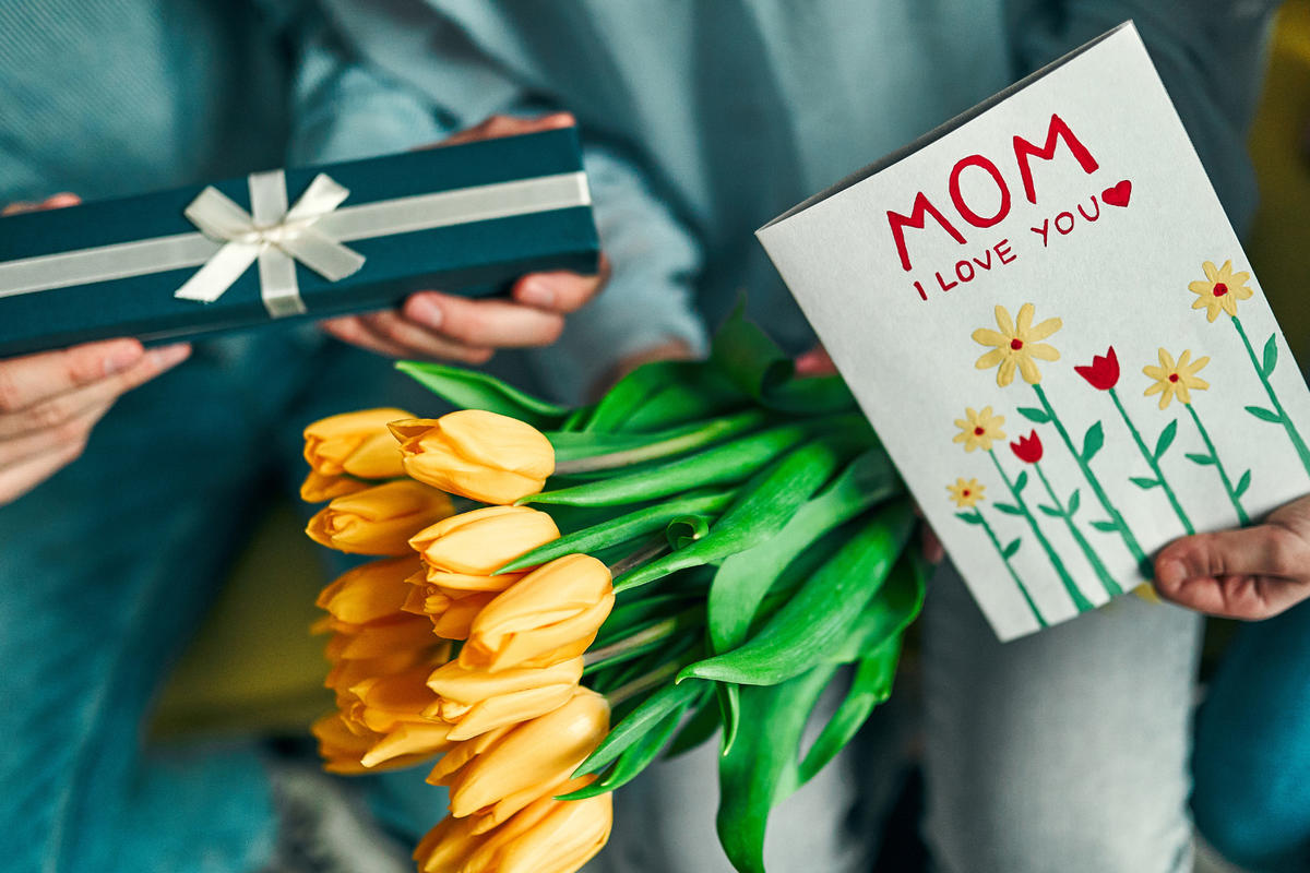 Closeup of Mother's Day celebration with yellow tulips, gift, and greeting card