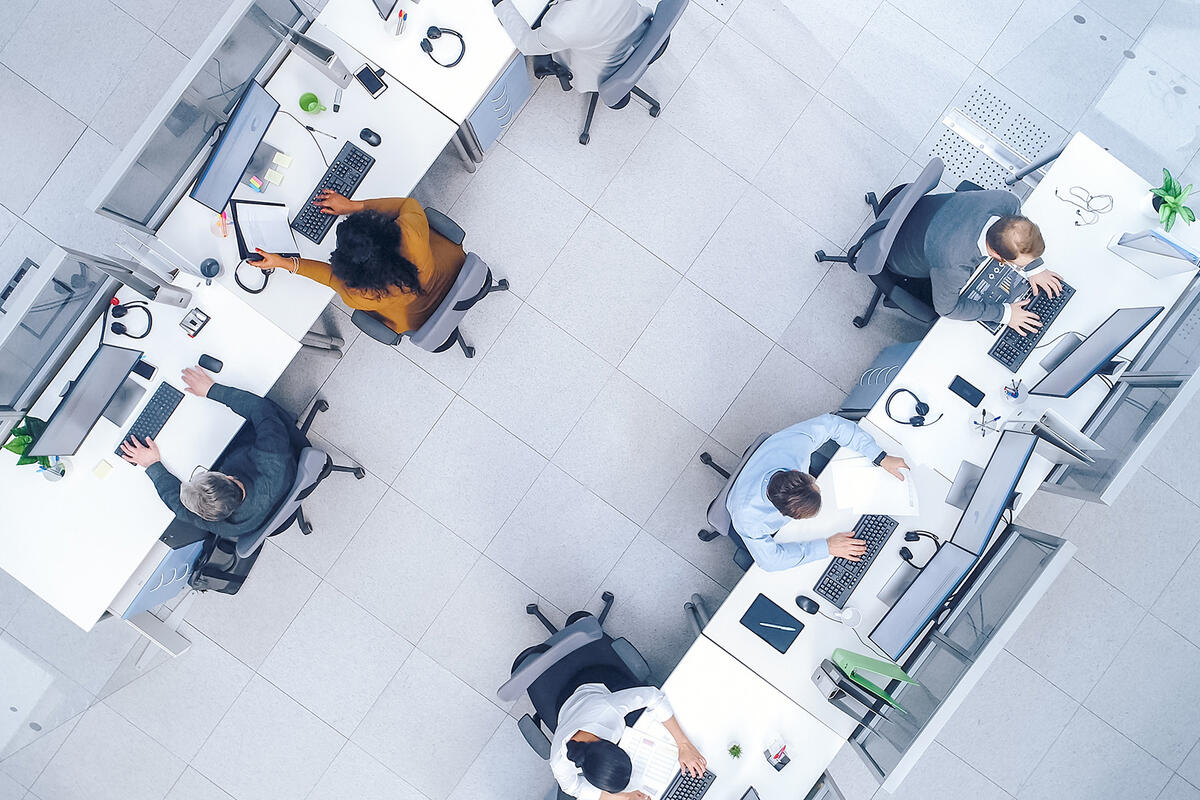 Top down shot of busy corporate office with rows off businessmen and women working on desktop computers