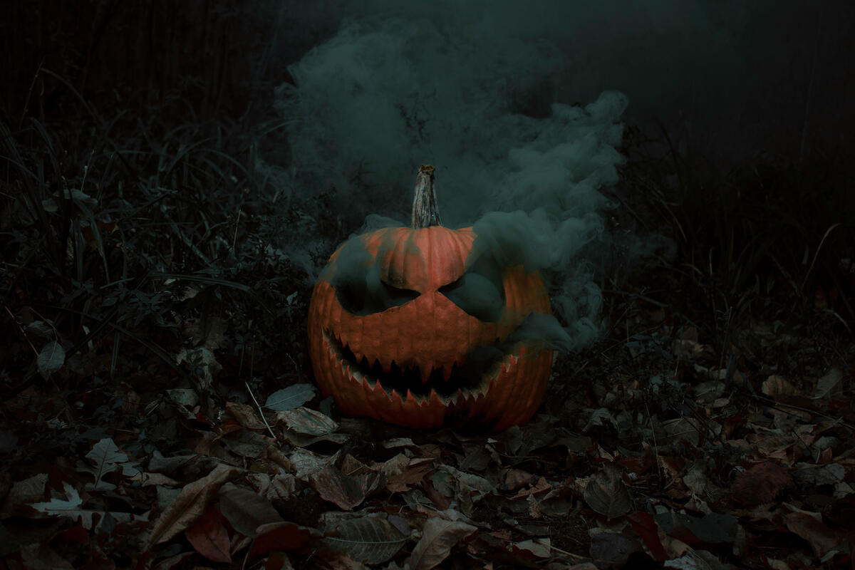 A spooky Halloween pumpkin with a menacing carved face, emitting thick smoke from its eyes and mouth