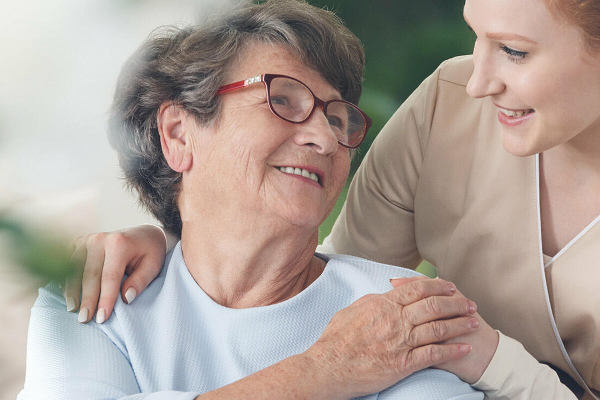 Smiling caregiver chatting with a senior woman in a joyful healthcare setting.