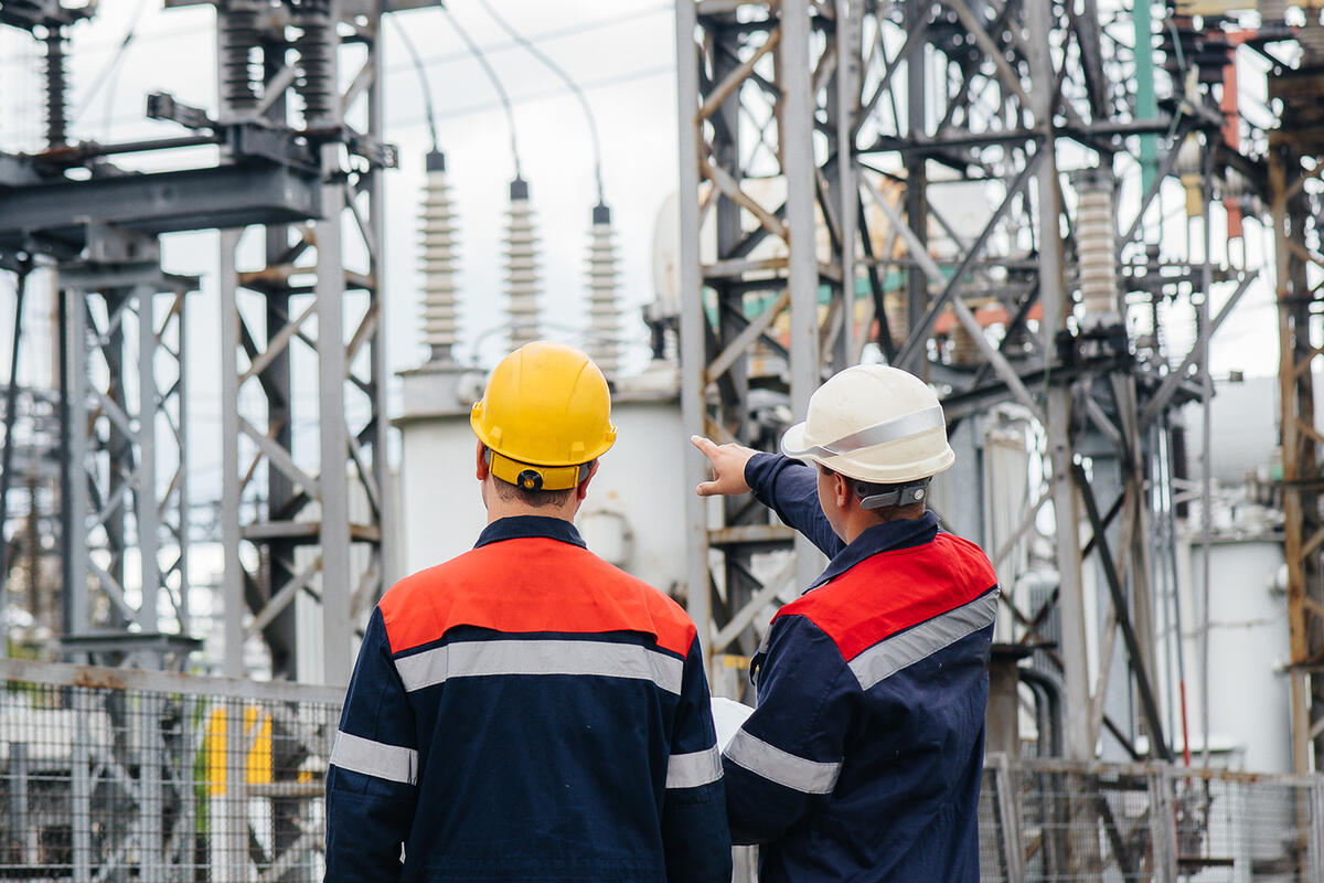 Two utility engineers inspecting modern high-voltage equipment at an electrical station.