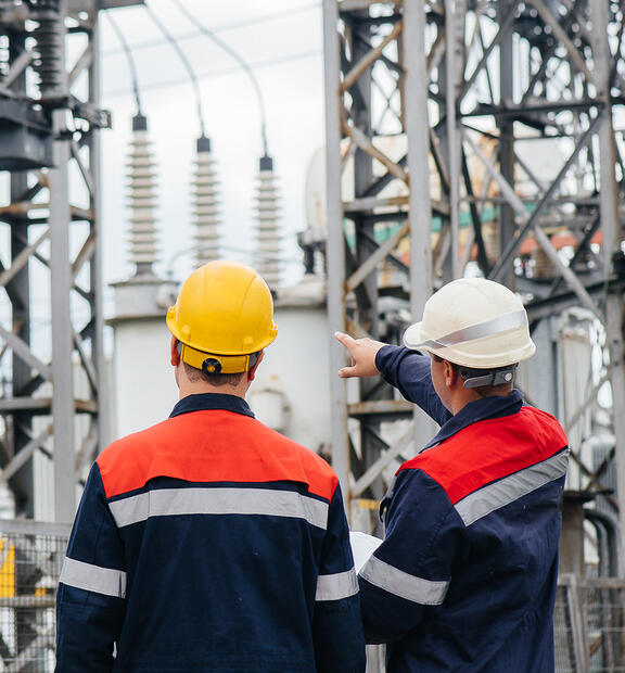 Two utility engineers inspecting modern high-voltage equipment at an electrical station.