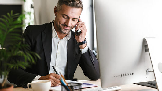 Happy man working in the office and talking on the phone