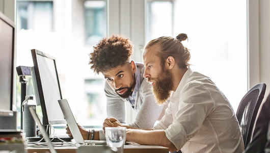 Two men looking at screens in the office