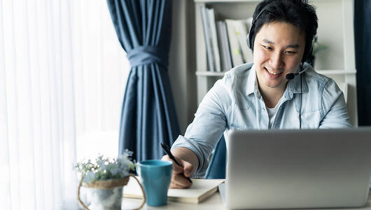 Asian guy with headset working remotely