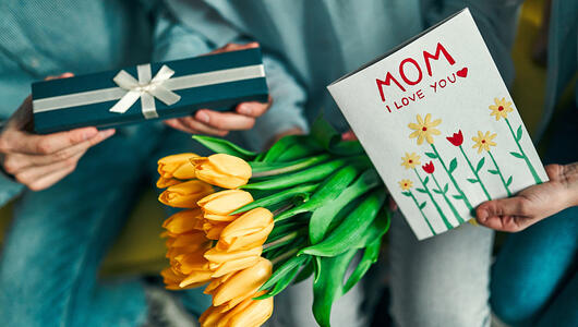Closeup of Mother's Day celebration with yellow tulips, gift, and greeting card