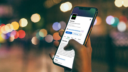 Closeup of hand holding device showing Hammer LinkedIn page