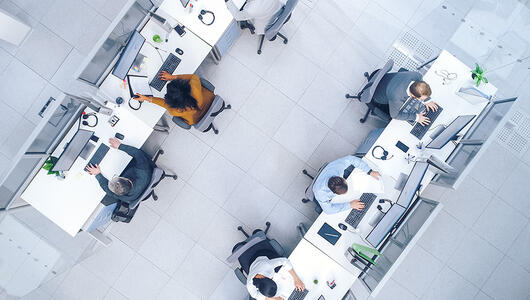 Top down shot of busy corporate office with rows off businessmen and women working on desktop computers