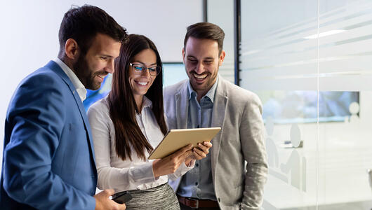 Happy business team looking at tablet together
