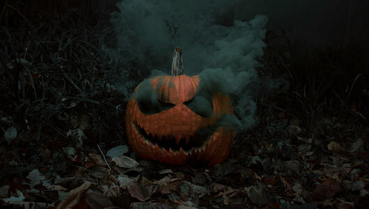A spooky Halloween pumpkin with a menacing carved face, emitting thick smoke from its eyes and mouth