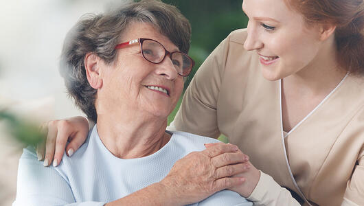 Smiling caregiver chatting with a senior woman in a joyful healthcare setting.
