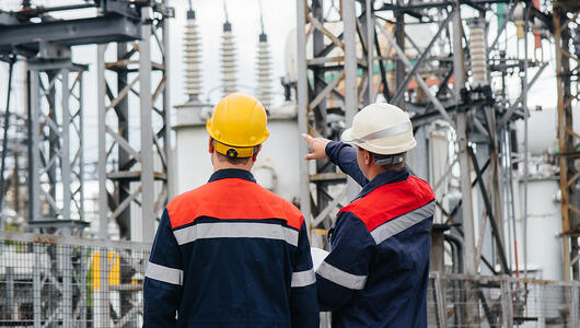 Two utility engineers inspecting modern high-voltage equipment at an electrical station.