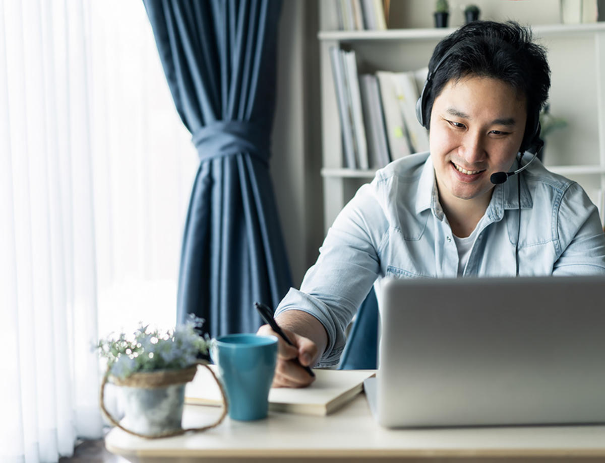 Asian guy with headset working remotely